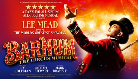 Text reads: "Bill Kenwright Ltd presents the Watermill Theatre production. Barnum The Circus Musical. 5 stars 'A Dazzling all-singing, all-juggling musical' The Observer. Lee Mead stars The World's Greatest Showman. Music by Cy Coleman. Lyrics by Michael Stewart. Books by Mark Bramble. Originally produced on the Broadway stage by Judy Gordon, Cy Coleman, Maurice and Lois F Rosenfeld in association with Irwin Feld and Kenneth Feld". On the right there is a man wearing an elaborate red jacket and black top hat. He is performing i=on stage in a circus tent.