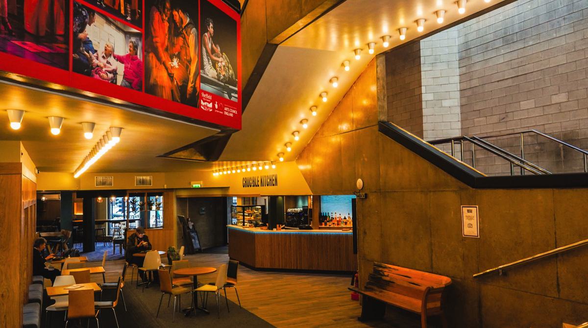 Image shows Crucible Kitchen situated in the lower foyer of the Crucible. A bar, tables and seating are visible in the image.