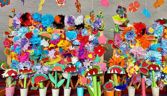 A colourful display of plants and flowers made out of card and craft materials.