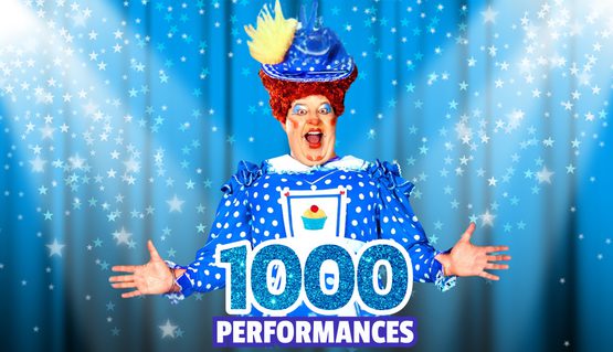 Dame Damian Williams in a blue dress above glittery text that reads: 1000 performances. Blue lights and stars glow behind him.