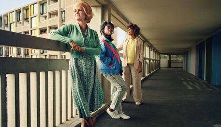 Standing at the Sky's Edge artwork with three women in period clothing from different times at the Park Hill flats.