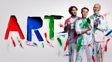 Promotional image for the play ART. 3 white males pose wearing white shirts and suits covered in green, red and blue paint. They holding paint brushes and rollers.