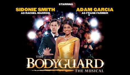 Text reads: 'The Bodyguard The Musical. Starring Sidonie Smith and Rachel Marron and Adam Garcia as Frank Farmer'. There is a woman wearing a gold dress and a man wearing a suit and tie. The woman is wearing elaborate jewellery and is smiling. The man has his hand out in front of her. There are paparazzi taking photos of her behind them.