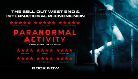 Promotional image for Paranormal Activity featuring a darkly lit room illuminated by a ghostly light as a person descends a staircase. Only their legs and torso are visible.