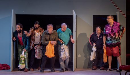 Six people peek through two doors and stand in a line across their thresholds. They all hold carrier bags and are crouched as if sneaking into the room.