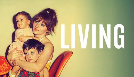 An old photograph of a young mother smiling, holding a toddler in one arm and hugging their other around a young child. They sit on an orange chair at a table. Text reads LIVING