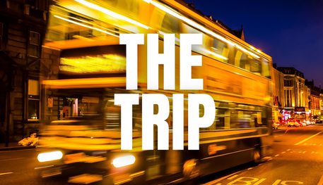 Promotional image for the trip featuring an out of focus bus travelling down a street at night time.