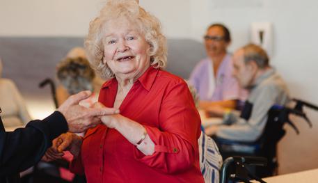 A Dementia Friendly Tea Dance at Sheffield Theatres. Photo by Becky Payne. An older woman holds someone’s hands as she dances. She has a big smile on her face.