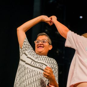 One person twirls another round holding their hand. They smile with laughter as they spin.