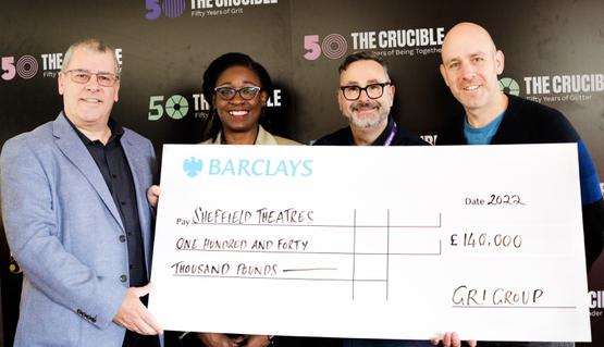 A group of people smile and hold a large cheque: a donation to Sheffield Theatres.