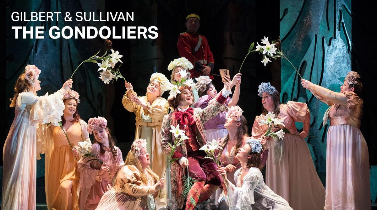 Text reads: 'Gilbert & Sullivan The Gondoliers'. The cast of The Gondoliers are performing on stage. They are wearing pale flowy dresses and holding up flowers.