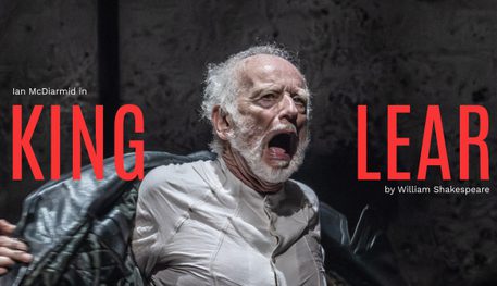 Ian McDiarmid (King Lear) in King Lear. Photo by Johan Persson. An older person with a white beard wears a long leather coat and shouts, ripping off their coat.