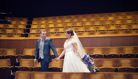 A bride and groom celebrate their wedding inside the Crucible Auditorium