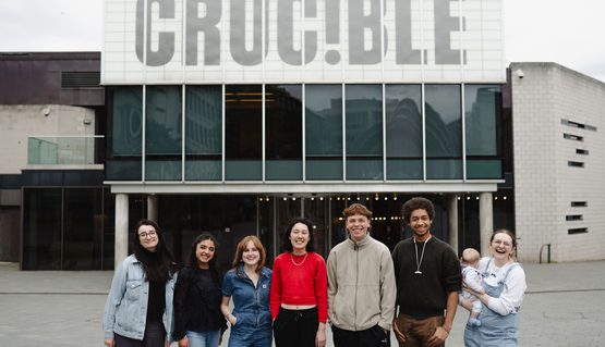 A group of people stand smiling in front of the Crucible theatre