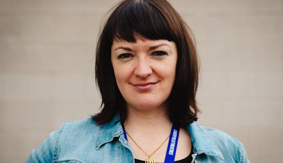 Headshot of Jenna Omeltschenko. Jenna has dark, shoulder length hair and wears a blue denim jacket.