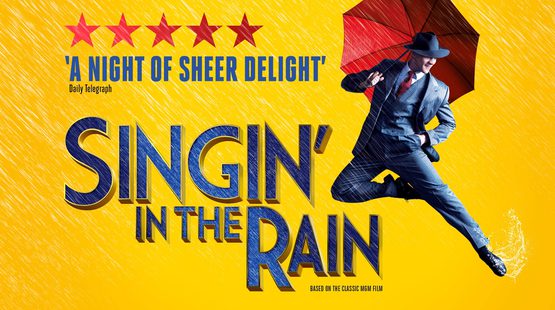 Promotional image for Singin' in the Rain. A man dressed in a suit and carrying an umbrella dances.