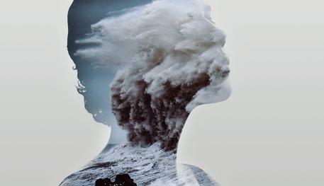 The profile of a person with their headed lifted against a grey background. Their outline is filled with the rushing waves of the sea.
