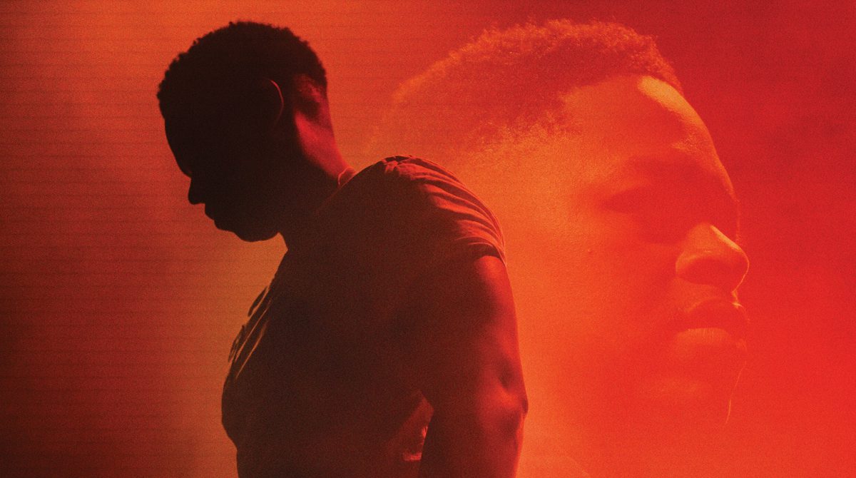 A silhouette of a man against a orange background which shows a face