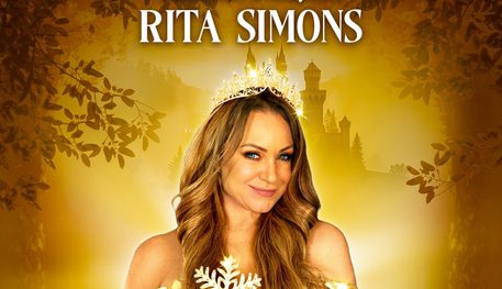 Against a golden background with tree branches and a castle, a person wearing a golden dress and holding a magic wand smiles.