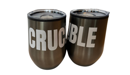 A pair of grey travel mugs with CRUCIBLE written on them