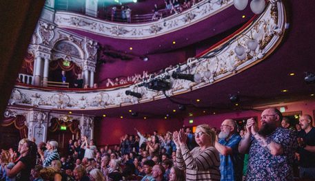 Wide shot of the Lyceum auditorium with a sold out audience clapping at the end of a show. Some audience members give a standing ovation.