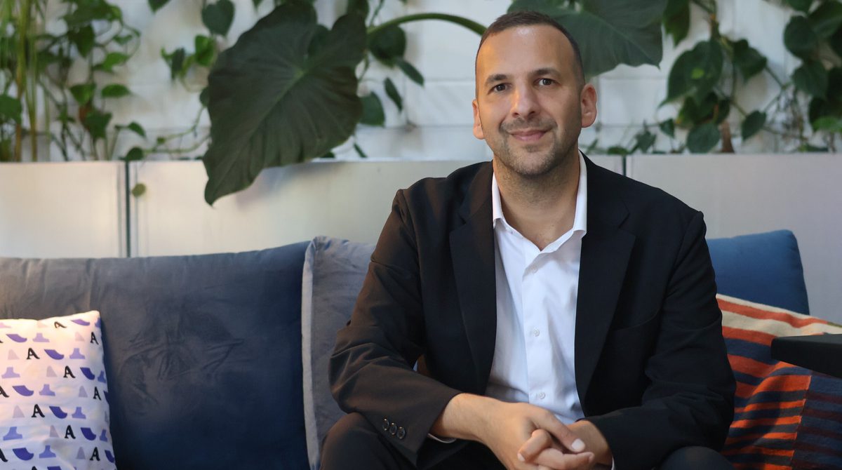 a photo of Zack Polanski sat down on a sofa.