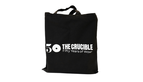 A black tote bag with the Crucible 50th anniversary logo