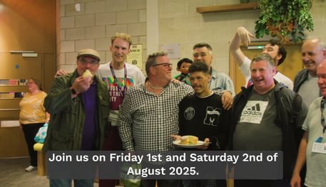 A group of people group together in the foyer of theTanya Moiseiwitsch Playhouse at Sheffield Theatres. They are all smiling, some have their arms around each other, some are holding slices of cake.